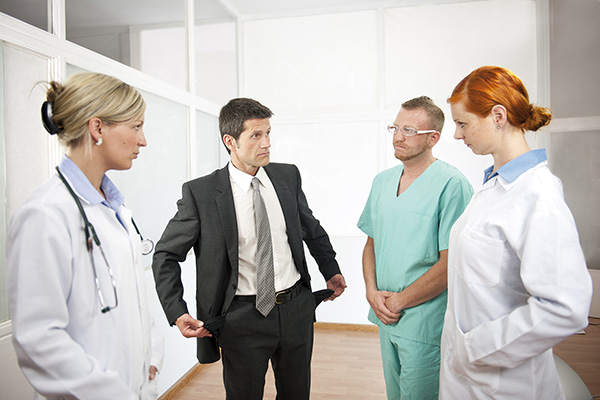 Businessman showing empty pockets to doctors